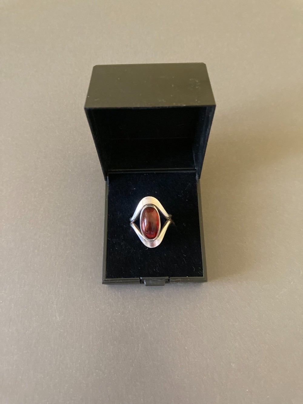 A mid-century Danish sterling silver ring featuring a central oval cabochon amber stone enclosed within a sculptural split-band frame. View VII