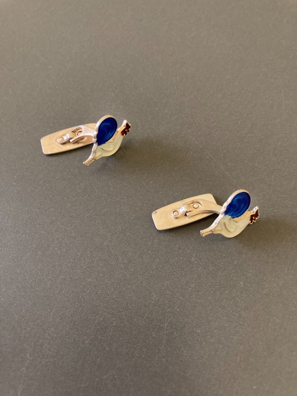 A pair of 1950s Danish sterling silver and enamel cufflinks shaped as cockerels with blue tails and white enamel bodies. View II