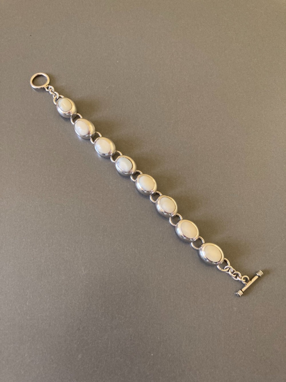 A Mexican sterling silver link bracelet featuring eight oval cabochon moonstones set in polished bezels with a toggle clasp attachment.