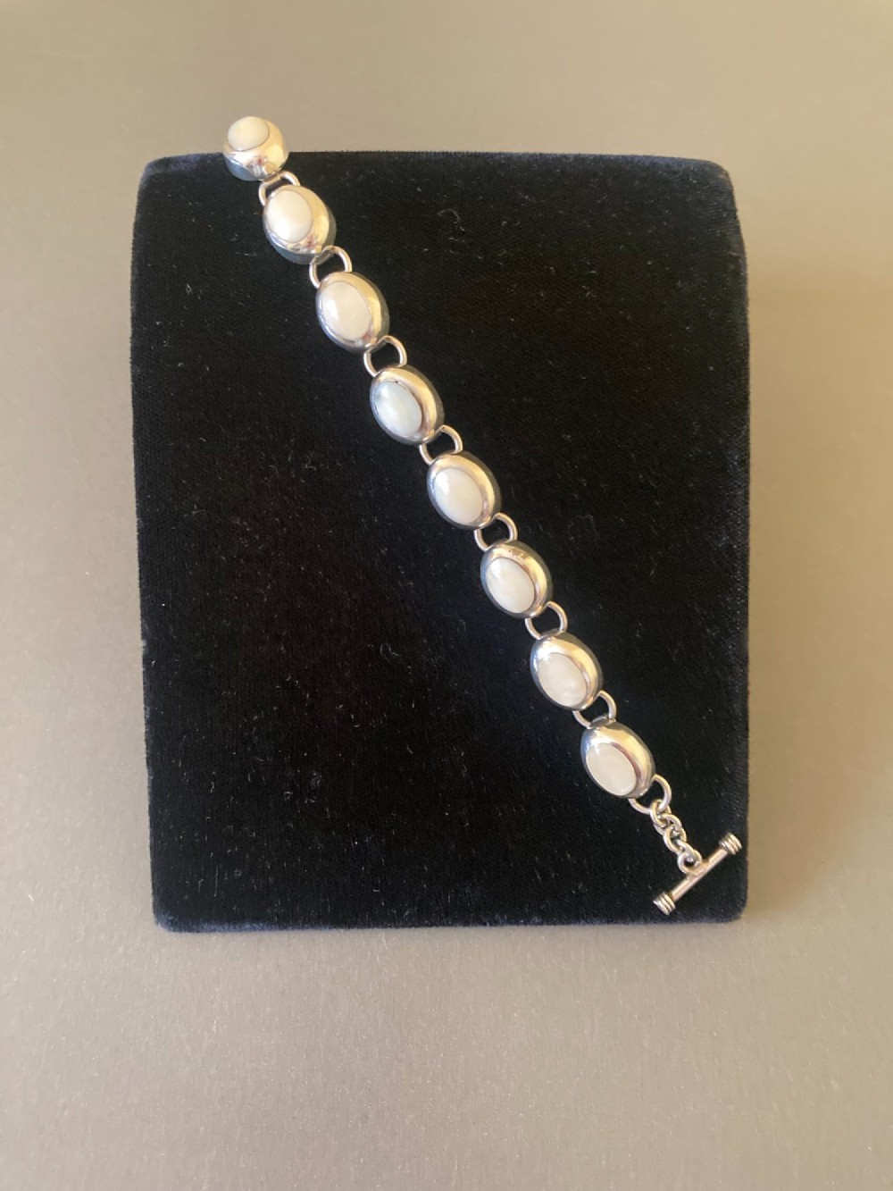 A Mexican sterling silver link bracelet featuring eight oval cabochon moonstones set in polished bezels with a toggle clasp attachment. View III