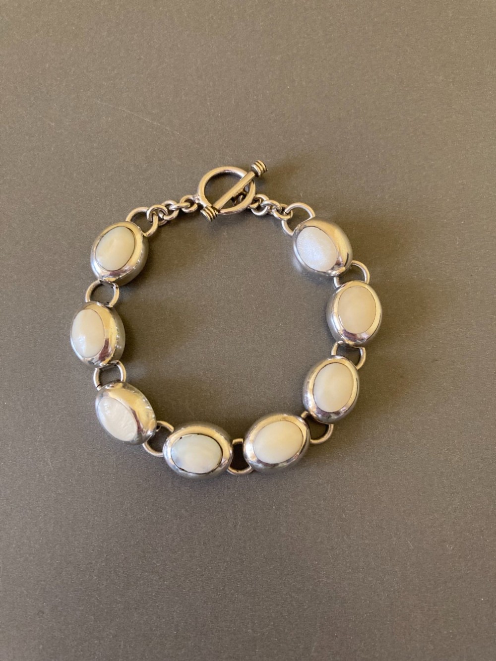 A Mexican sterling silver link bracelet featuring eight oval cabochon moonstones set in polished bezels with a toggle clasp attachment. View IV