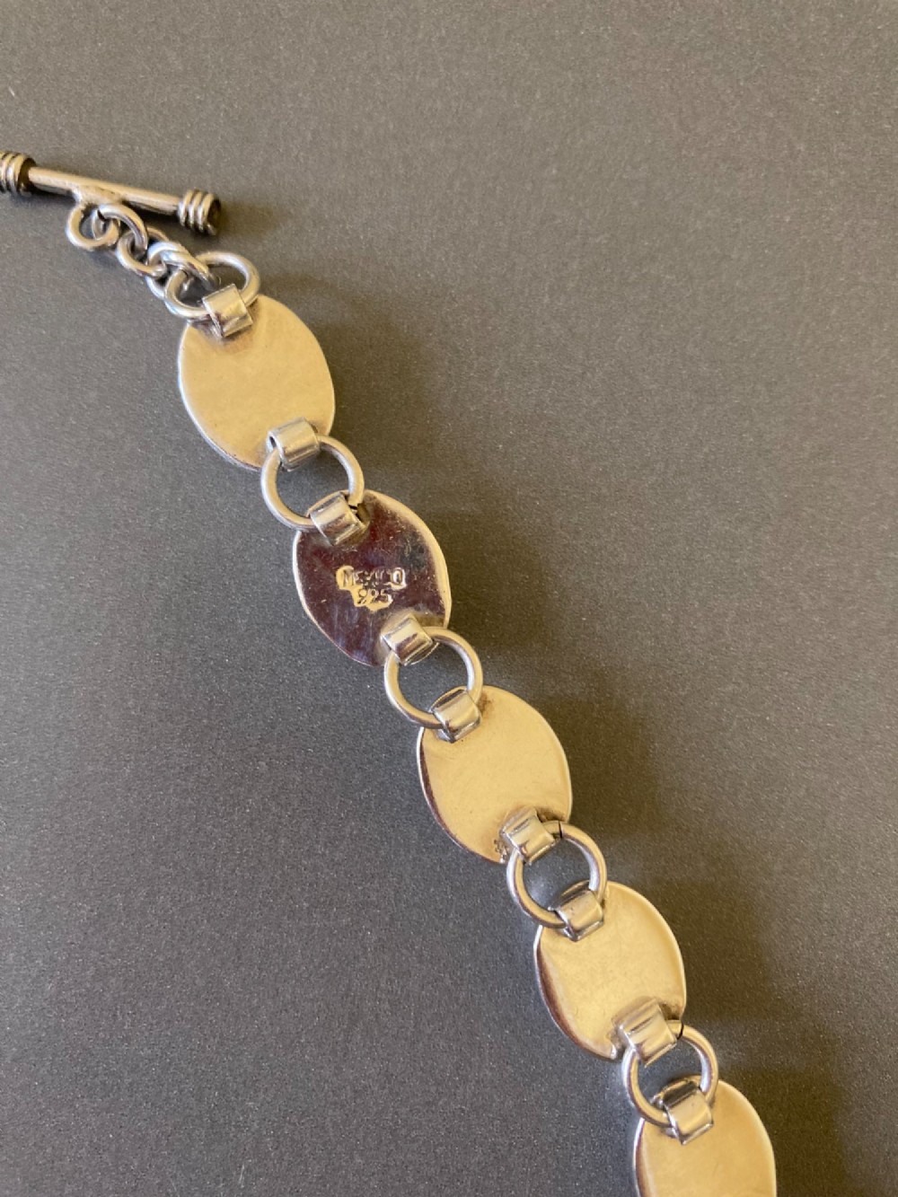 A Mexican sterling silver link bracelet featuring eight oval cabochon moonstones set in polished bezels with a toggle clasp attachment. View VI