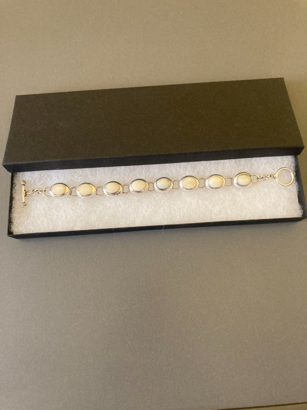 A Mexican sterling silver link bracelet featuring eight oval cabochon moonstones set in polished bezels with a toggle clasp attachment. View VII
