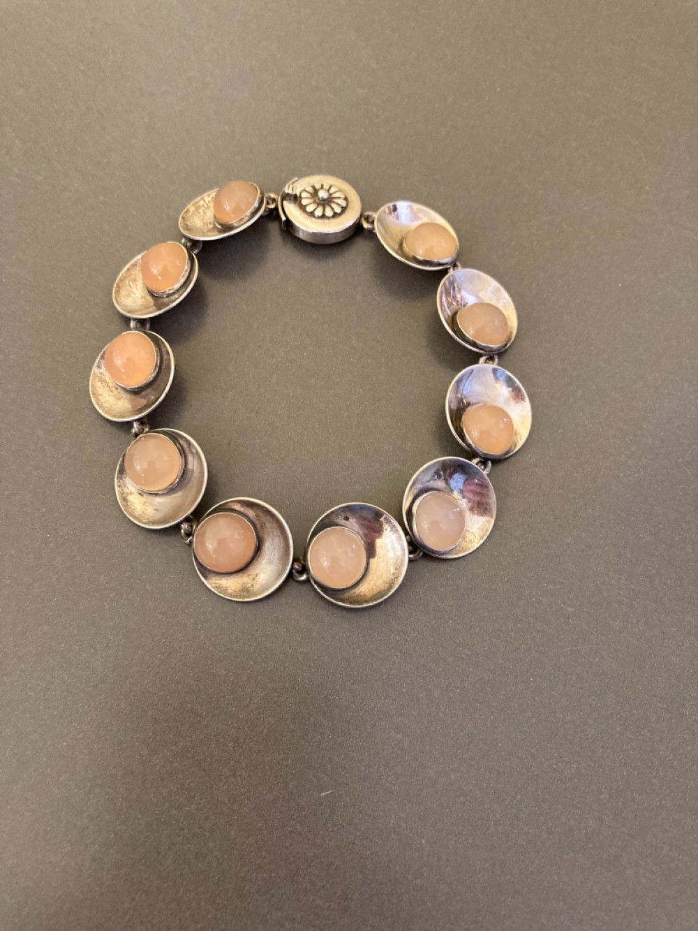 A Danish modernist sterling silver link bracelet set with round pale pink rose quartz cabochons in concaved circular mounts with a floral-detailed clasp.