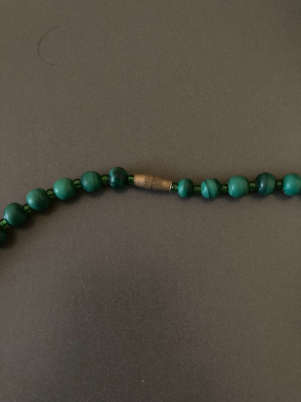 A 1950s strand of graduated, polished green malachite beads arranged in a heart shape with a brass screw clasp. View V