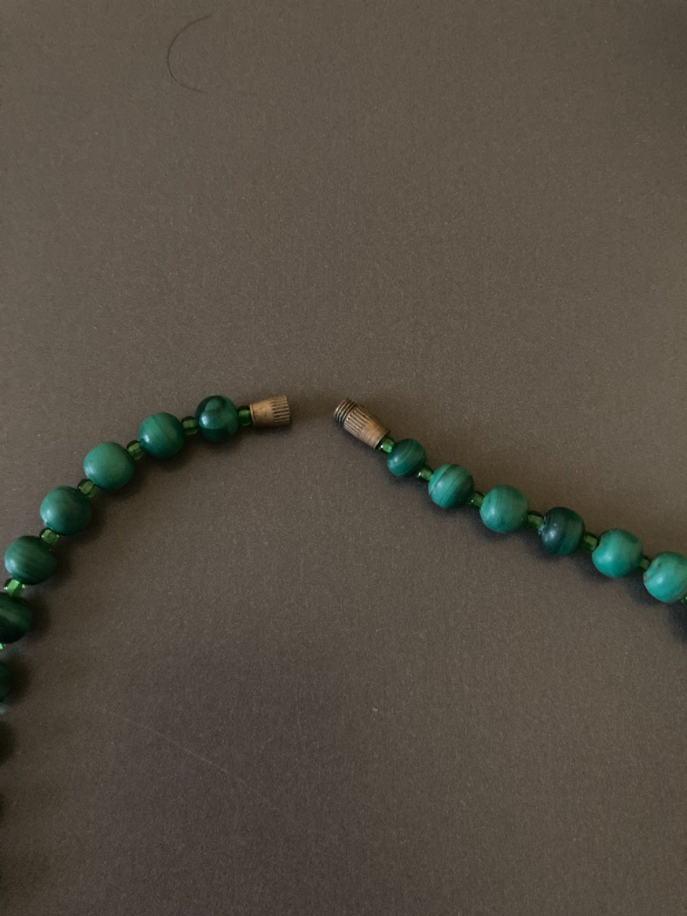 A 1950s strand of graduated, polished green malachite beads arranged in a heart shape with a brass screw clasp. View VI