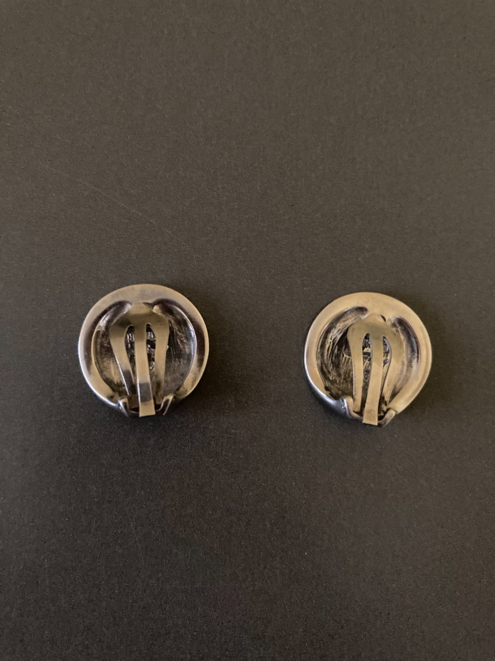 A pair of circular Danish sterling silver clip-on earrings featuring a smooth, minimalist curved profile. View IV