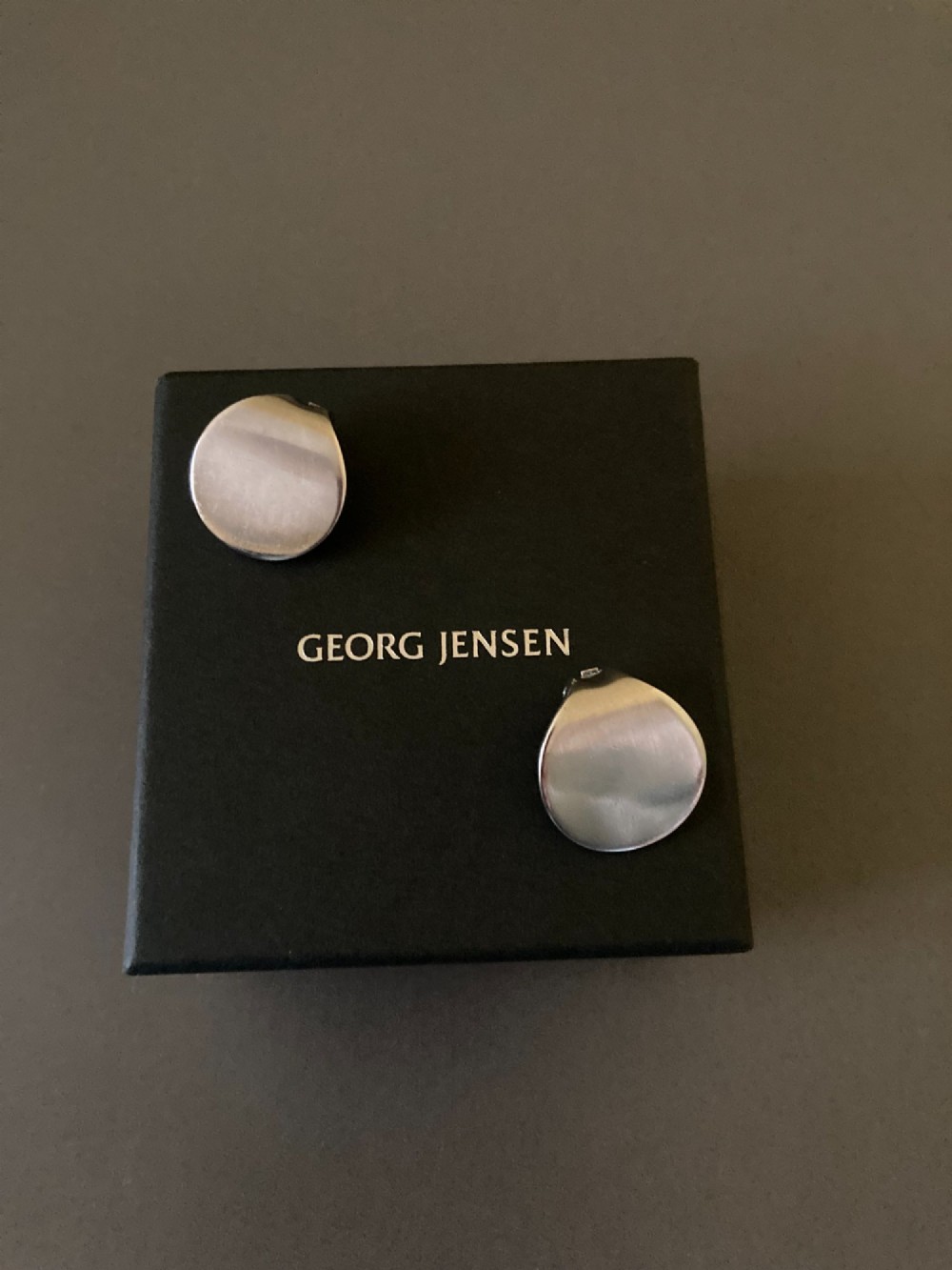 A pair of circular Danish sterling silver clip-on earrings featuring a smooth, minimalist curved profile. View V