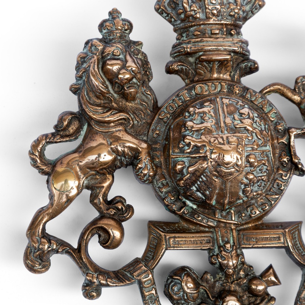 A cast brass wall plaque depicting the British Royal Coat of Arms featuring a lion and unicorn flanking a central shield and crown. View II