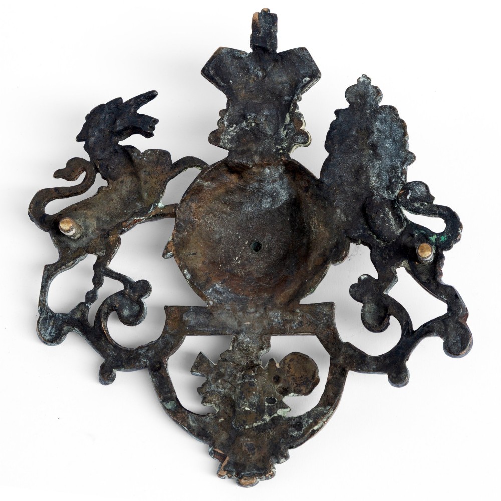 A cast brass wall plaque depicting the British Royal Coat of Arms featuring a lion and unicorn flanking a central shield and crown. View VI