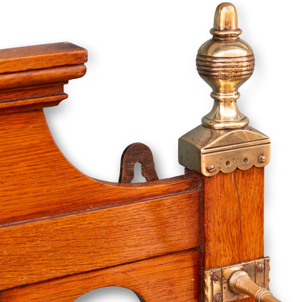 A wall-mounted golden oak coat rack featuring brass hooks, brass finials, a central bevelled mirror, and a small central storage box. View II