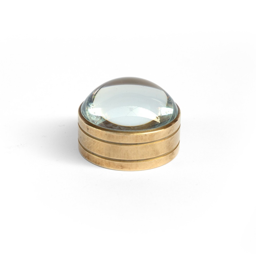 A solid circular brass mounted glass dome desk magnifying lens shown on a white background. View II