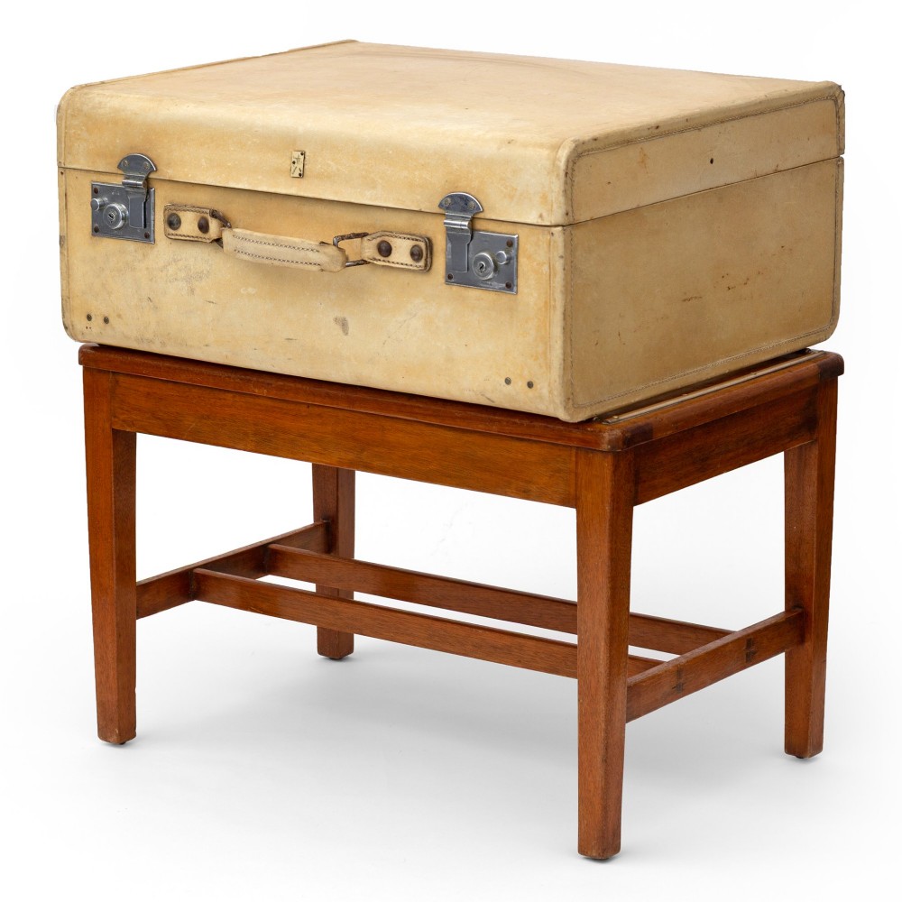 A low rectangular polished oak luggage stand featuring slatted timber top rails inset with protective brass strips supported by four square tapered legs. View II