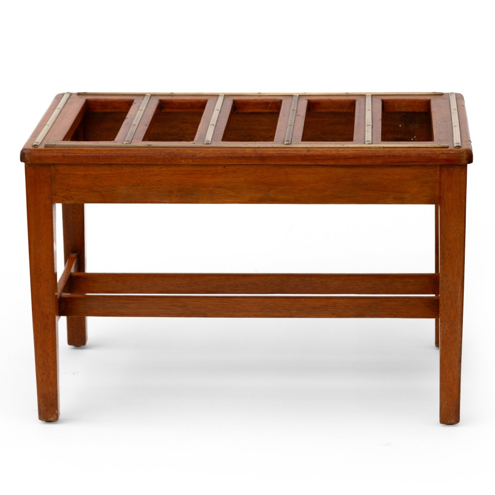 A low rectangular polished oak luggage stand featuring slatted timber top rails inset with protective brass strips supported by four square tapered legs. View III