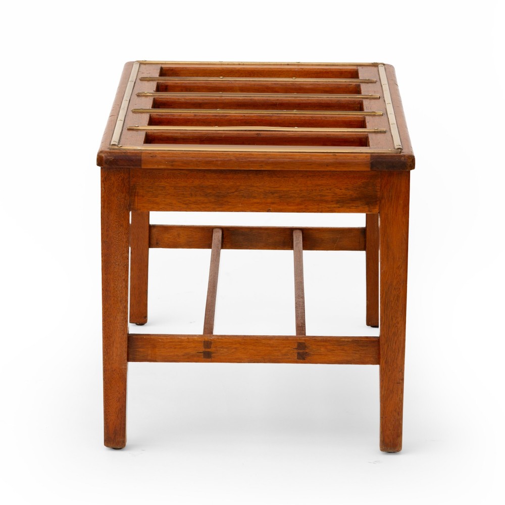 A low rectangular polished oak luggage stand featuring slatted timber top rails inset with protective brass strips supported by four square tapered legs. View IV