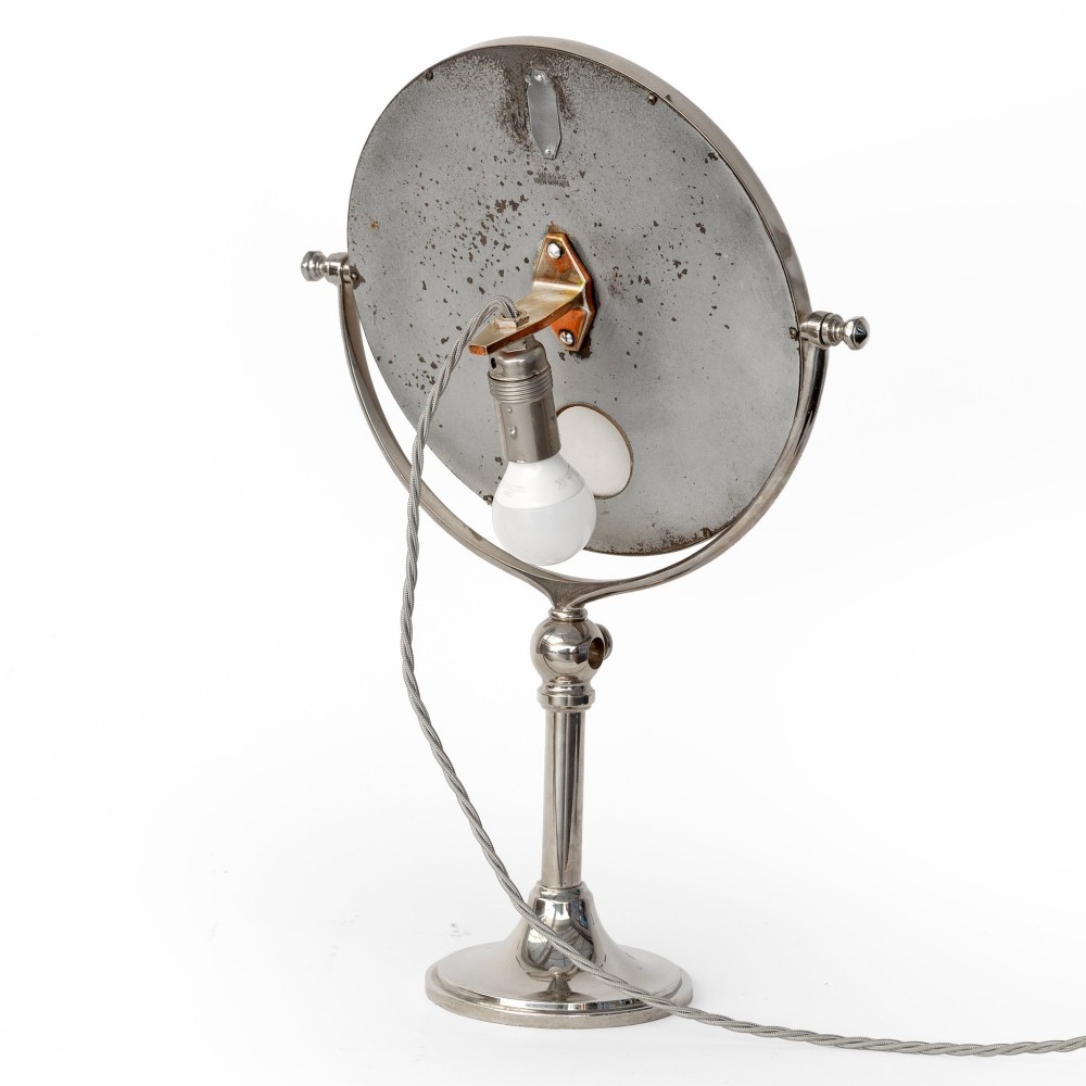 A nickel-plated circular vanity mirror featuring an adjustable swivel stem, circular weighted base, integrated central lens, and braided electrical cord. View II