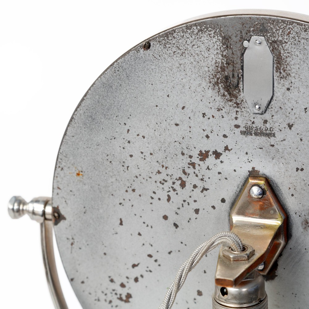 A nickel-plated circular vanity mirror featuring an adjustable swivel stem, circular weighted base, integrated central lens, and braided electrical cord. View III