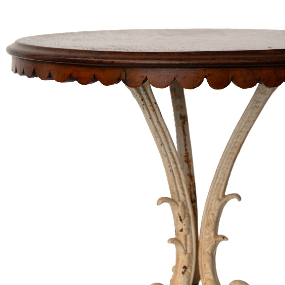 A Victorian cast iron tripod table featuring an off-white painted base with scroll motifs and a circular dark wood top with a scalloped edge. View III