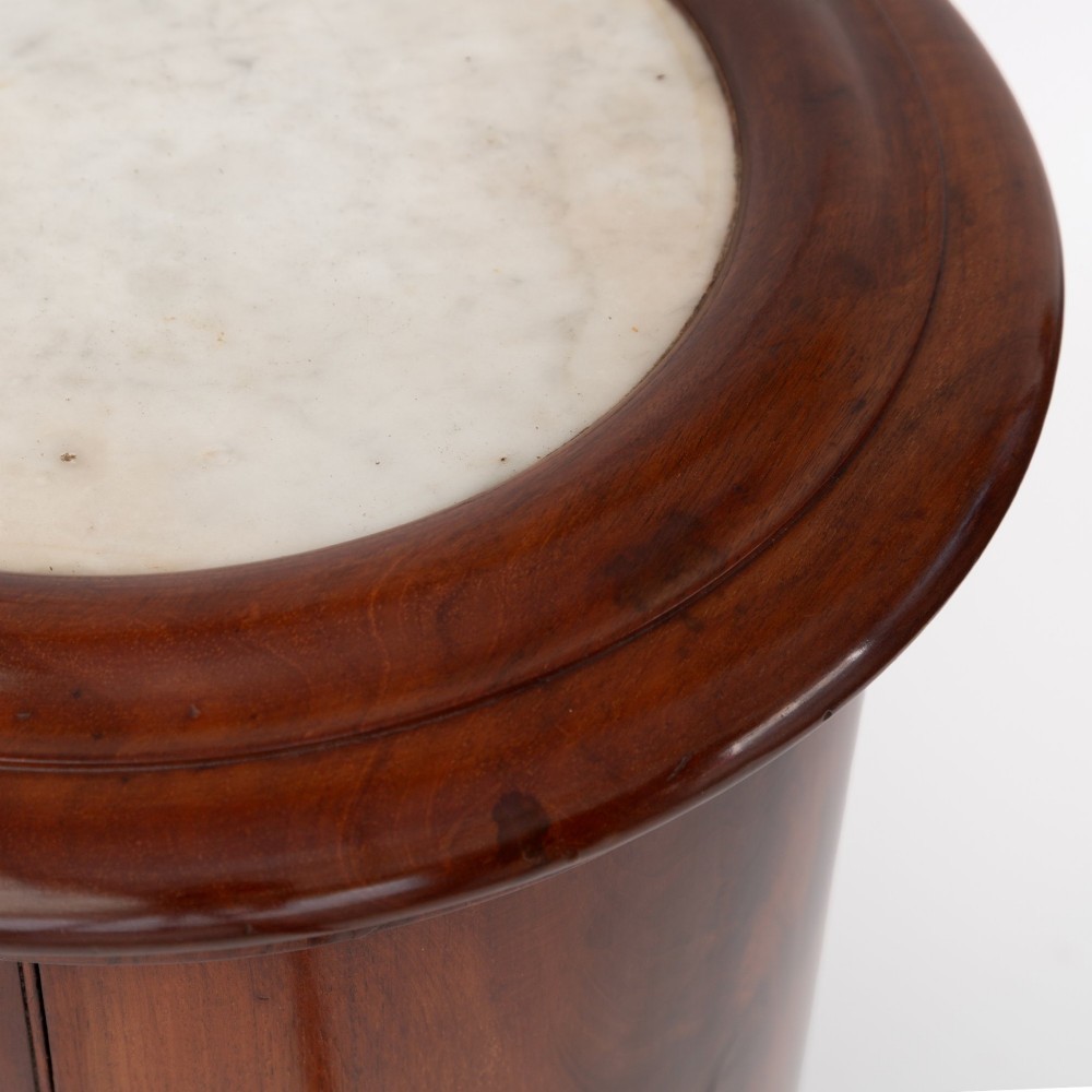 A Victorian cylindrical figured mahogany pot cupboard featuring a single curved door and an inset marble top. View IV