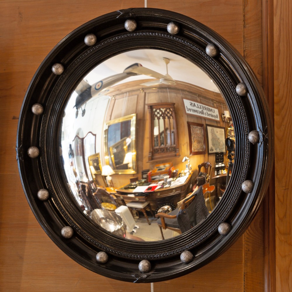 A circular ebonised wood convex mirror featuring a moulded frame adorned with silver ball embellishments around the inner perimeter.