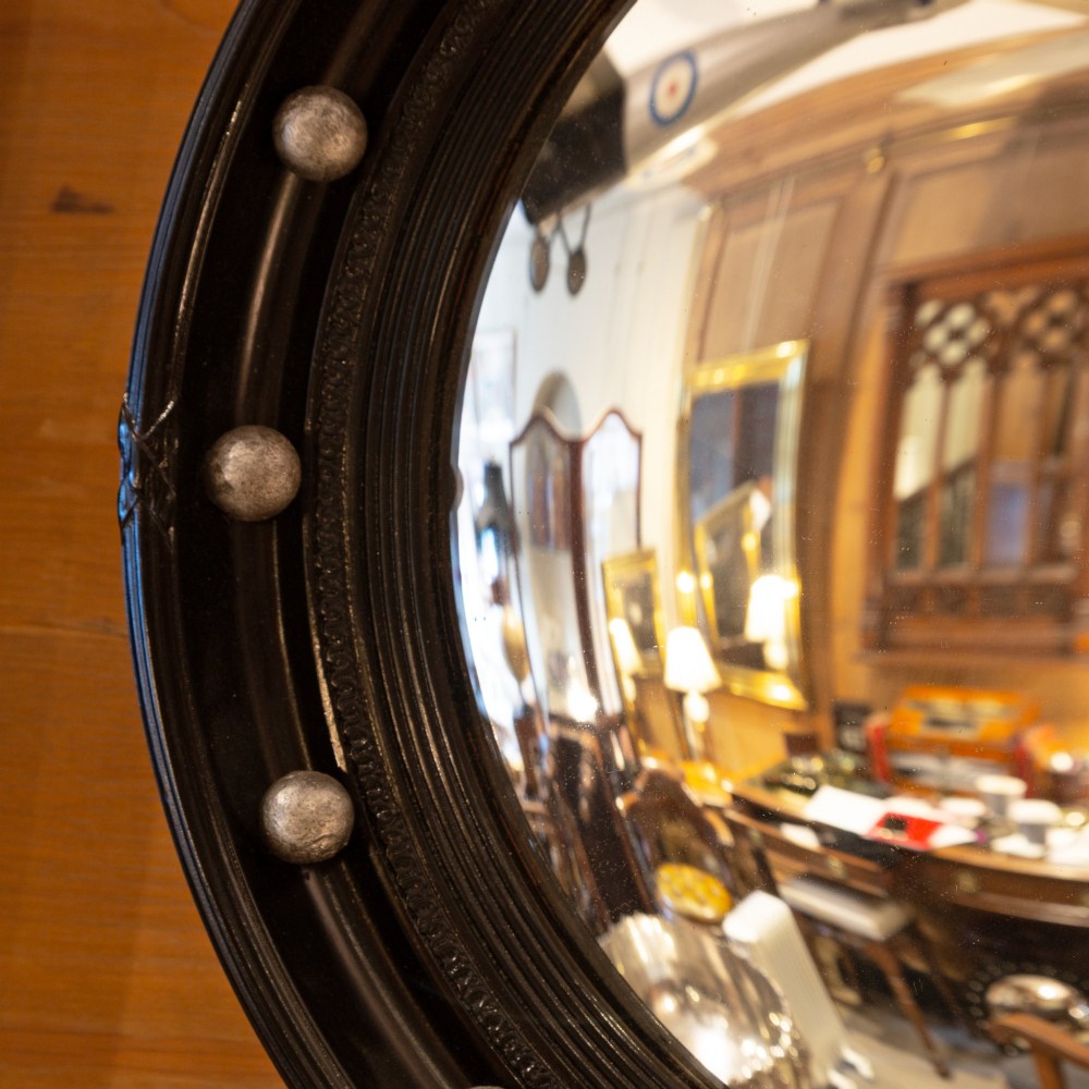 A circular ebonised wood convex mirror featuring a moulded frame adorned with silver ball embellishments around the inner perimeter. View II