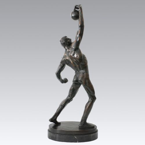 fig 1. An Art Deco dark patinated bronze sculpture depicting a muscular male figure lifting a weight overhead on an oval dark base.
