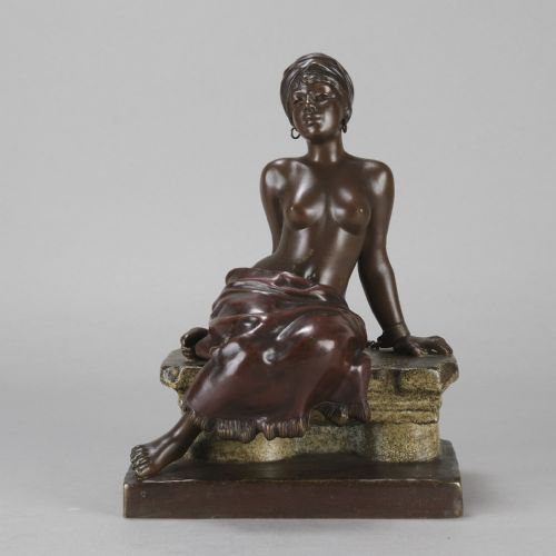 fig 1. A dark brown patinated bronze sculpture of a seated figure wearing a headwrap and draped skirt, resting on a textured base.