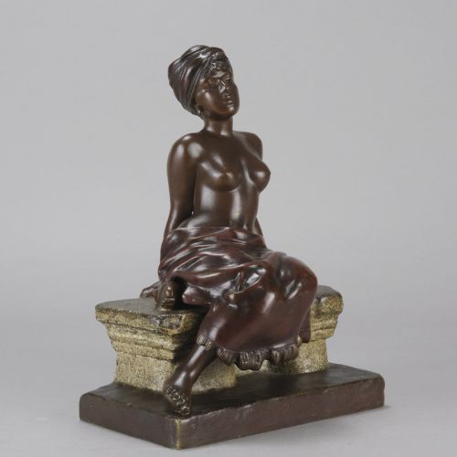fig 2. A dark brown patinated bronze sculpture of a seated figure wearing a headwrap and draped skirt, resting on a textured base.