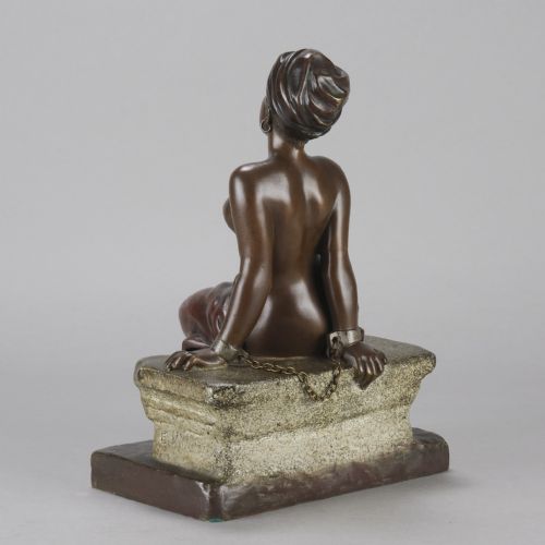 fig 4. A dark brown patinated bronze sculpture of a seated figure wearing a headwrap and draped skirt, resting on a textured base.