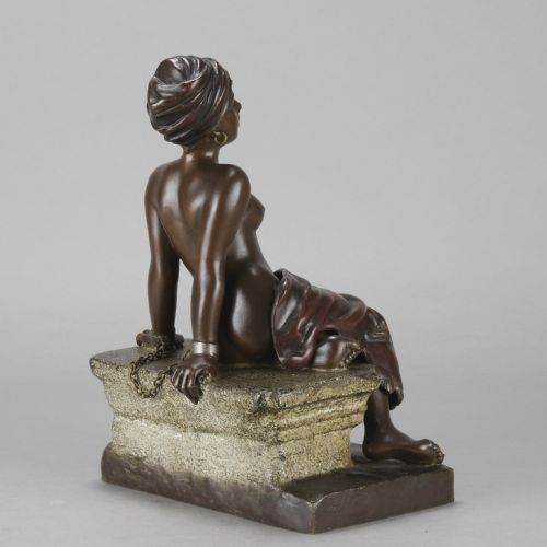 fig 5. A dark brown patinated bronze sculpture of a seated figure wearing a headwrap and draped skirt, resting on a textured base.