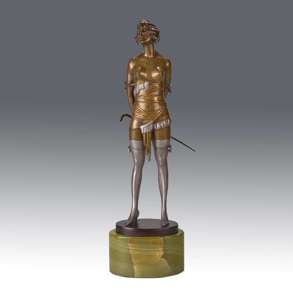 An Art Deco patinated bronze sculpture of a female figure with silvered stockings holding a riding crop behind her back, raised on a green onyx cylindrical base.