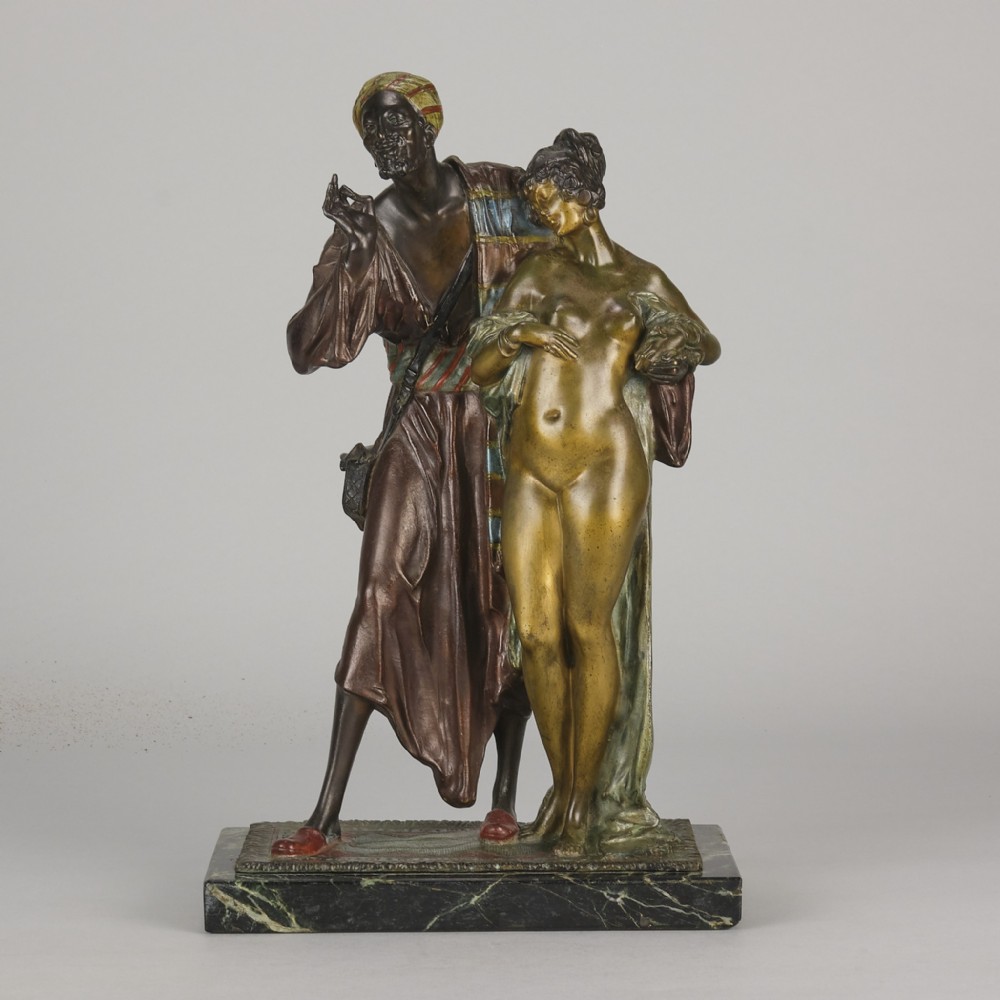 An early 20th-century cold-painted bronze Orientalist figure group mounted on a rectangular dark green veined marble base.
