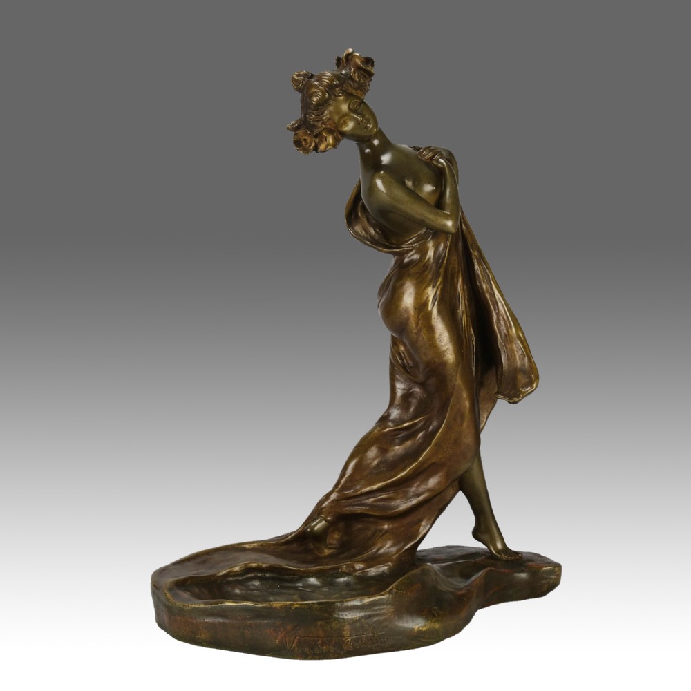 A late 19th-century Art Nouveau patinated bronze figure of a draped female standing on an organic tray base.