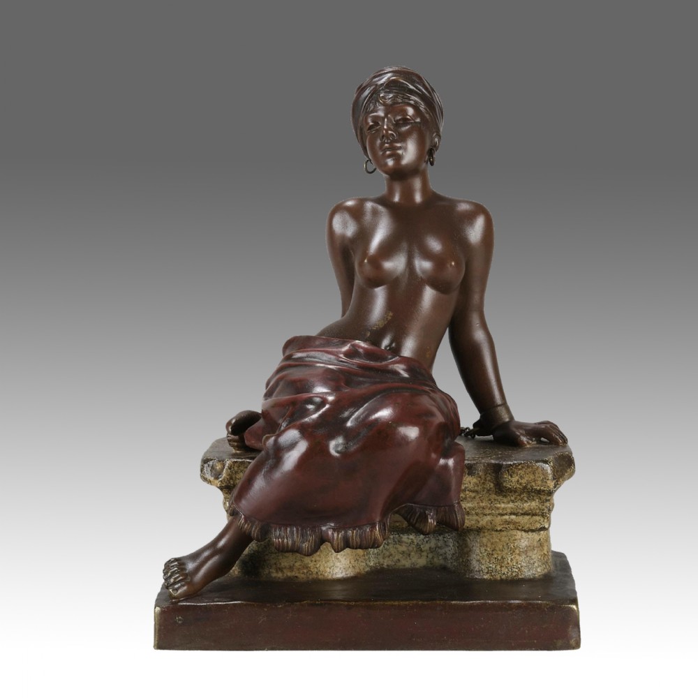 A dark brown patinated bronze sculpture of a seated figure wearing a headwrap and draped skirt, resting on a textured base.