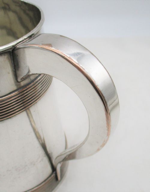 fig 1. A Georgian Old Sheffield silver-plated quart tankard featuring a tapered body with reeded copper bands and a curved handle.