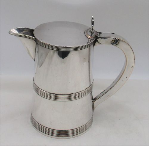 fig 1. A 19th-century silver-plated beer jug with a hinged lid, reeded horizontal bands, and a sturdy curved handle.