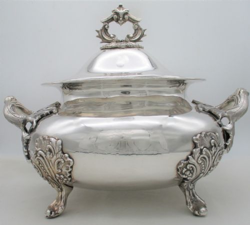 fig 1. A large 19th-century silver-plated soup tureen featuring leaf-form handles, a domed lid with a scroll finial, and four scroll feet.
