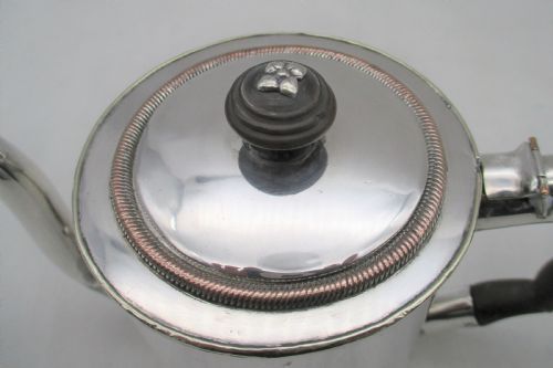 fig 1. A Georgian Old Sheffield silver-plated argyle gravy warmer featuring a cylindrical body, curved gooseneck spout, fitted lid, and carved wooden handle.
