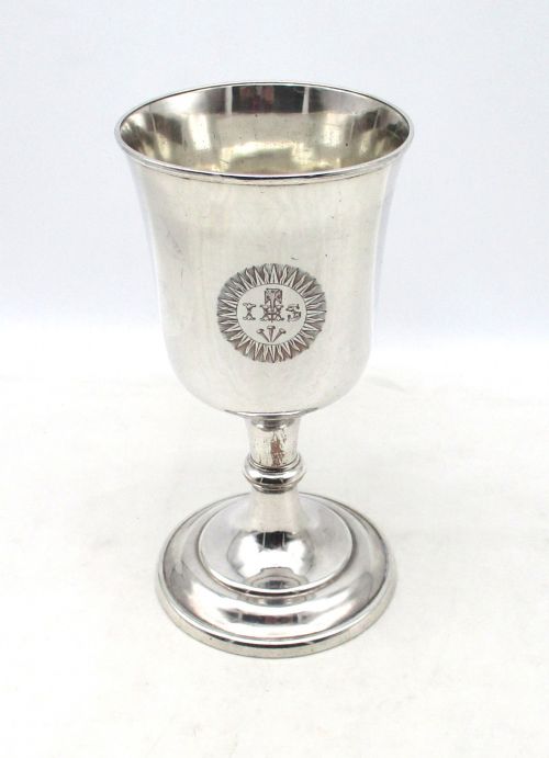 fig 1. A 19th-century silver-plated church chalice featuring a flared cup with an engraved IHS Christogram medallion, a knopped stem, and a stepped circular base.