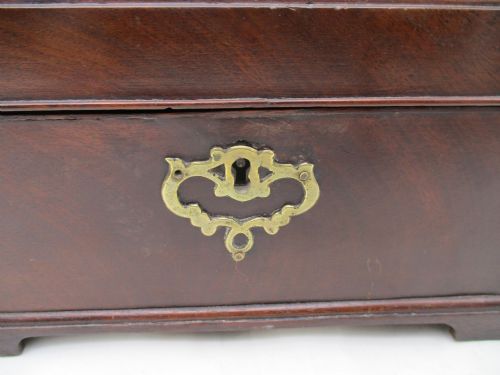 fig 1. A rectangular George III mahogany tea caddy featuring a stepped hinged lid, a brass swan-neck handle, and a pierced brass keyhole escutcheon.