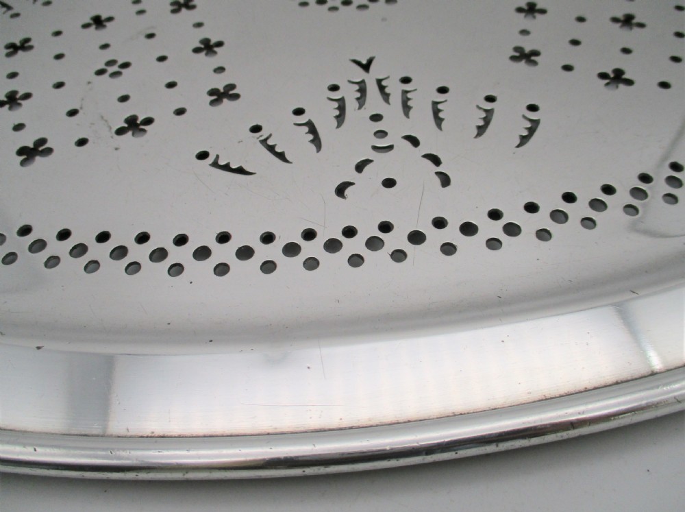 An oval 19th-century silver-plated mazarine draining tray featuring intricate pierced geometric patterns and foliate scrollwork. View VII