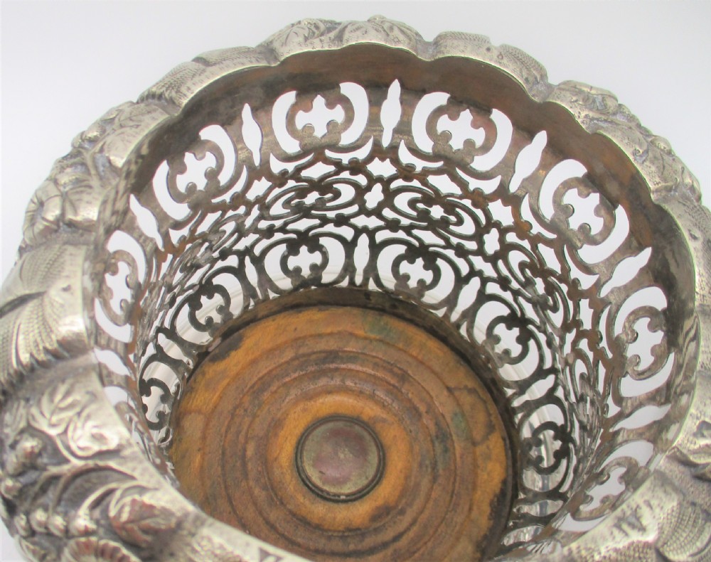 A pair of mid-19th-century silver-plated wine bottle coasters featuring pierced lattice sides, floral repousse borders, and turned wooden bases. View IV