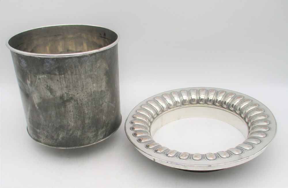 An antique silver-plated urn-shaped wine cooler featuring gadrooned lower details, twin scroll handles, engraved leaf motifs, and subtle copper exposure along worn edges. View VI