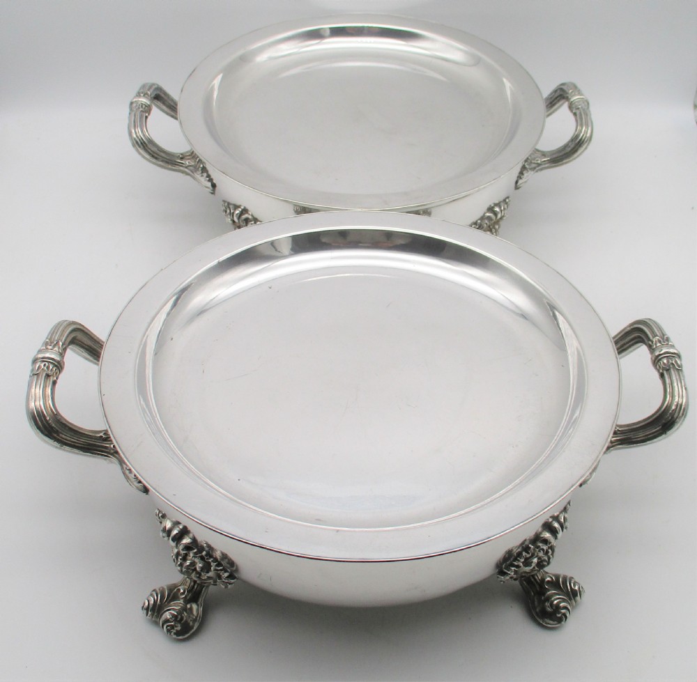 A pair of 19th-century circular silver-plated warming dishes featuring twin handles and ornate cast feet. View II