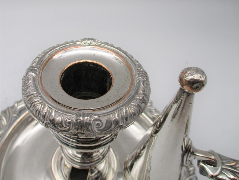 A pair of silver-plated chamber candlesticks featuring wide circular scroll-rimmed bases, integrated finger handles, and removable conical candle snuffers. View V
