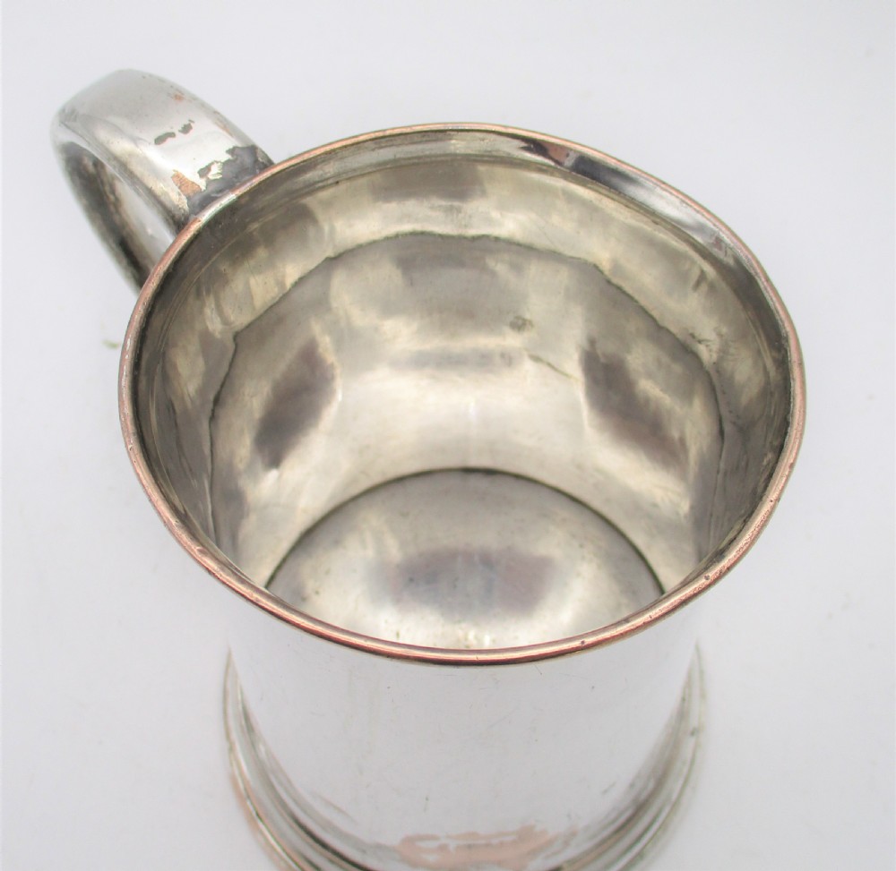 An 18th-century Old Sheffield silver-plated pint tankard with a curved handle and visible copper exposure along the rim and base. View IV