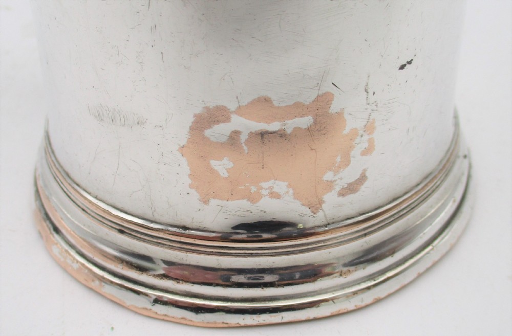 An 18th-century Old Sheffield silver-plated pint tankard with a curved handle and visible copper exposure along the rim and base. View V