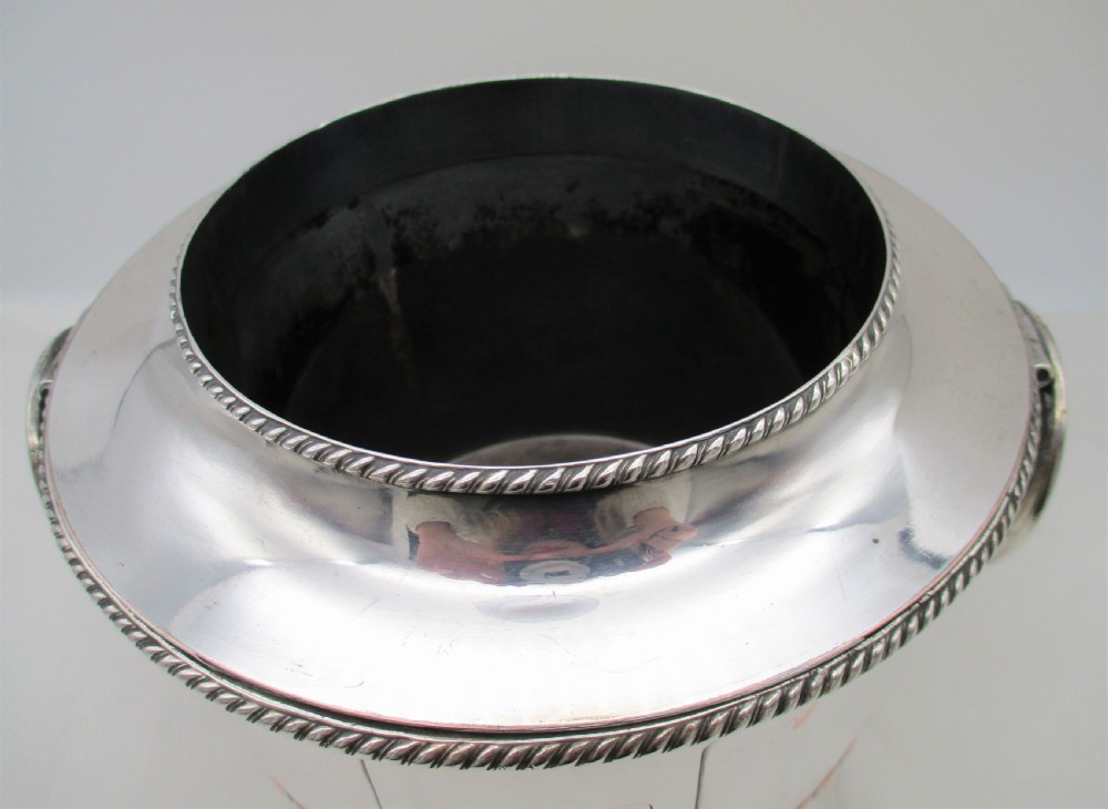 An urn-shaped Old Sheffield Plate wine cooler with a fluted lower body showing copper wear, engraved shield monogram, and gadrooned borders. View III