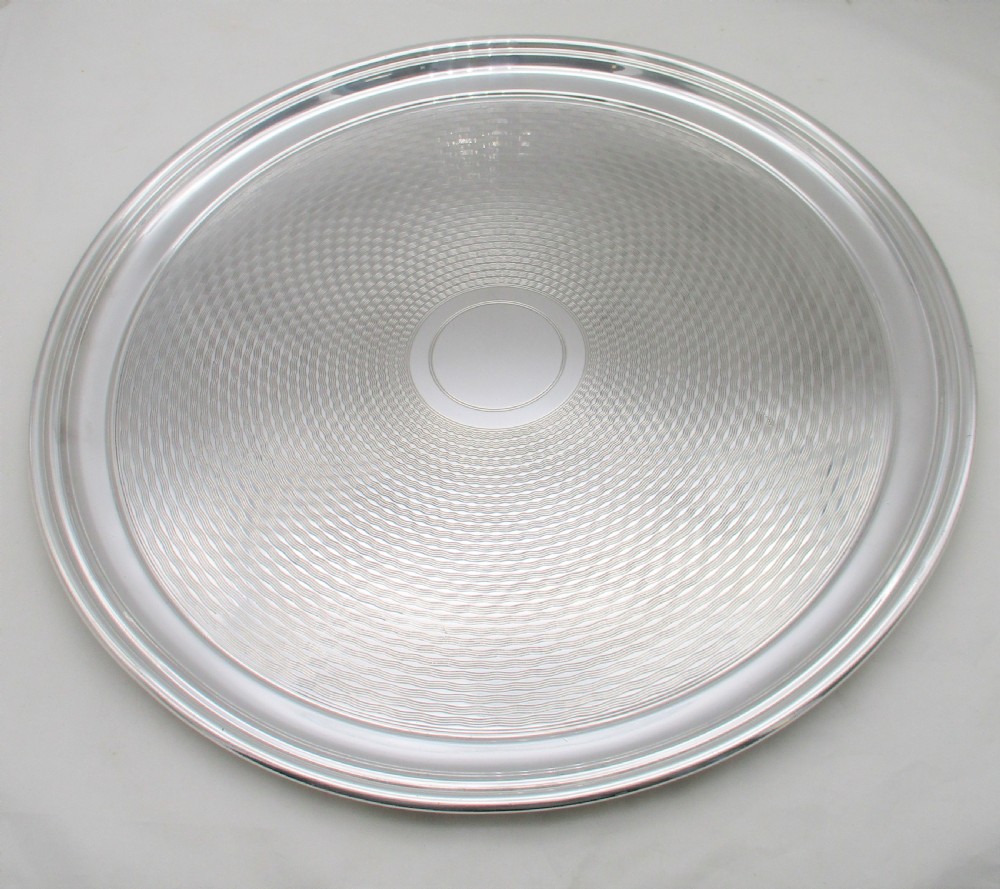 A round silver-plated cocktail tray with engine-turned concentric patterning and an unengraved central circular cartouche.