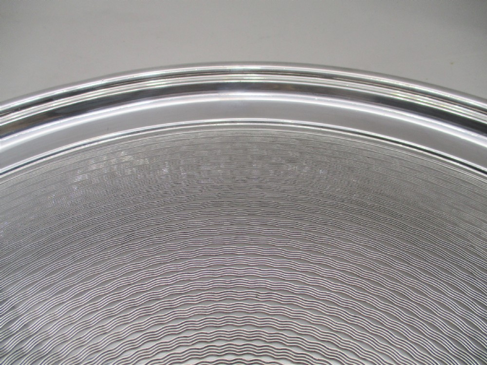 A round silver-plated cocktail tray with engine-turned concentric patterning and an unengraved central circular cartouche. View IV